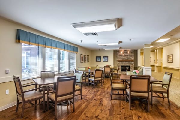 Cozy dining area with wooden tables and chairs, featuring a fireplace.