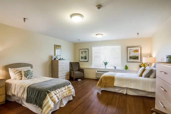 A cozy shared bedroom with two beds, dressers, and art on the walls.