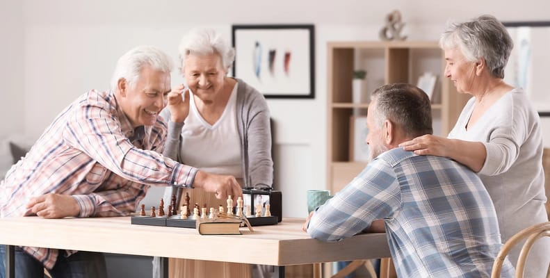 Four seniors playing chess at a table