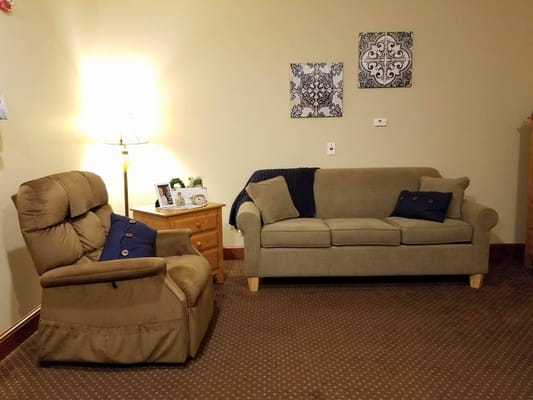 Living room area with a recliner, sofa, and lamp