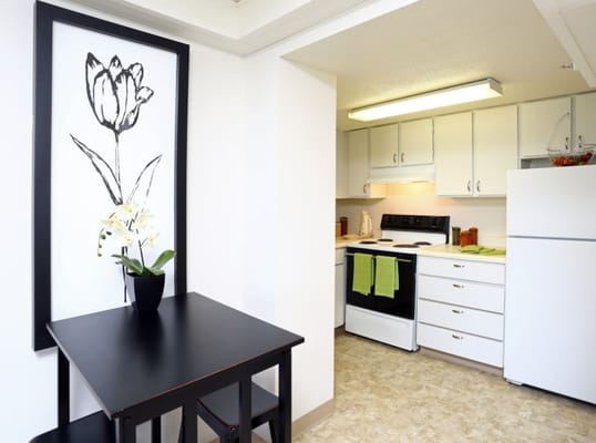 A modern kitchen space with a black table and white cabinetry.