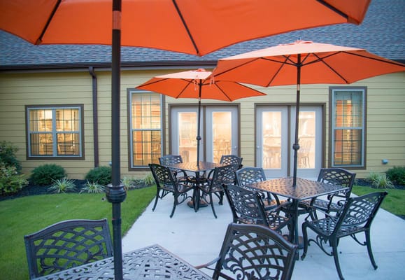 Outdoor seating area with orange umbrellas at Woodcrest Assisted Living