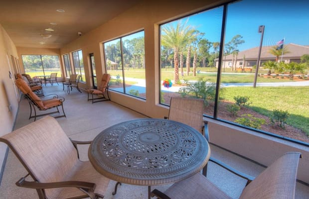 Outdoor seating area with tables and chairs next to a garden