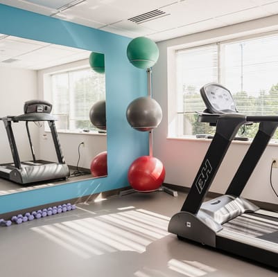 Treadmill and exercise equipment in a bright fitness room