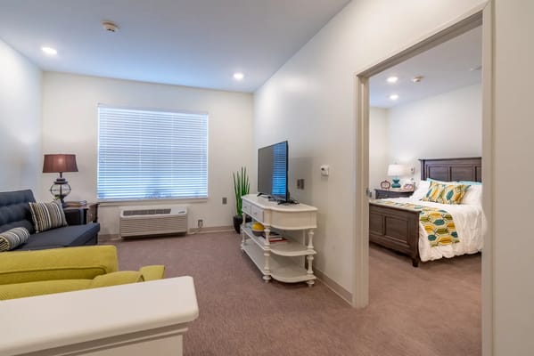 Living room with a sofa, TV, and entrance to a bedroom.