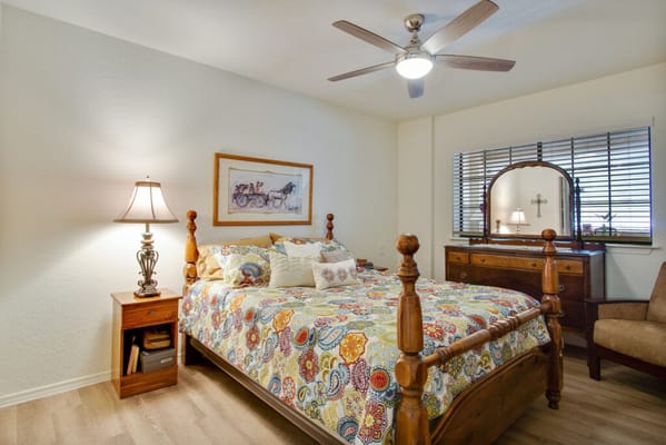 A colorful bedroom featuring a wooden bed, bedside lamp, and dresser.
