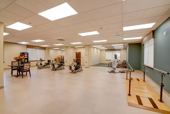 Spacious rehabilitation room with exercise equipment and a table