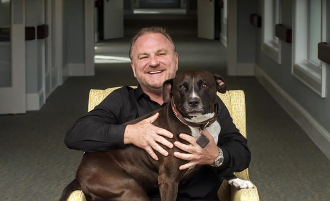 Smiling man holding a dog in a hallway