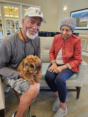 Residents enjoying time with a small dog in a common area