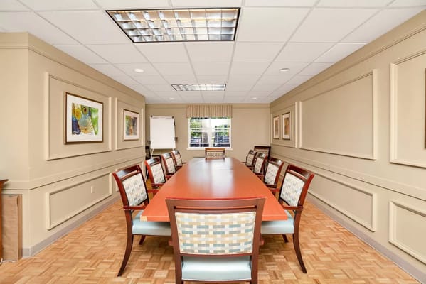 A spacious conference room with a long table and chairs.