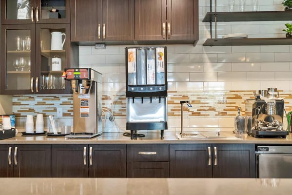 A coffee station with various beverages and equipment in a kitchen