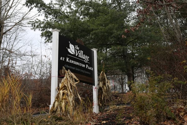 The Village at Kensington Place sign amidst autumn foliage