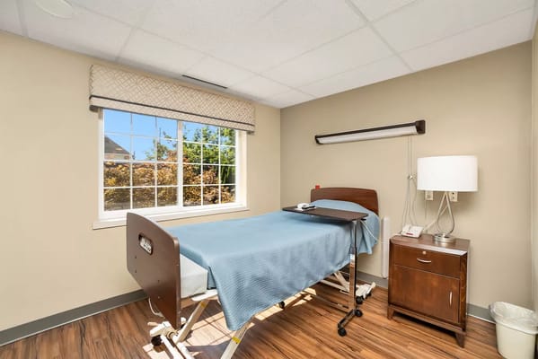 A patient room with a bed, side table, and window