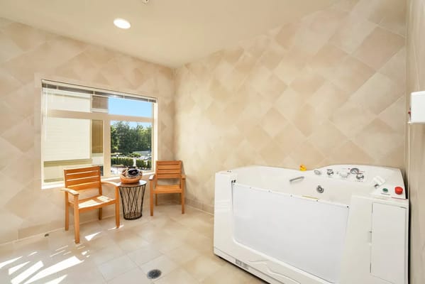 Bright bathroom featuring a therapeutic tub and seating area