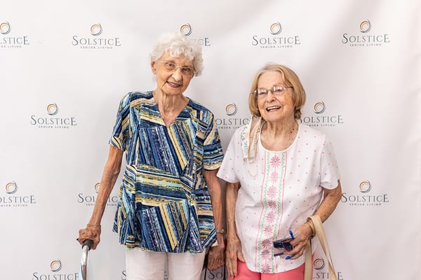 Two smiling residents posing together in a lobby area