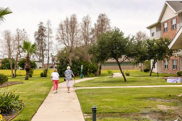 Residents walking along a pathway in the facility grounds