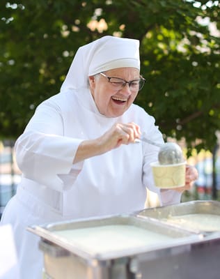 A smiling nun serving food outside