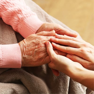 Close-up of elderly hands being held in comfort