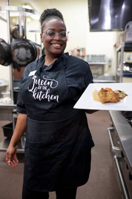 Staff member presenting a plate of food in the kitchen