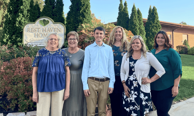 Group of staff members outside the facility sign