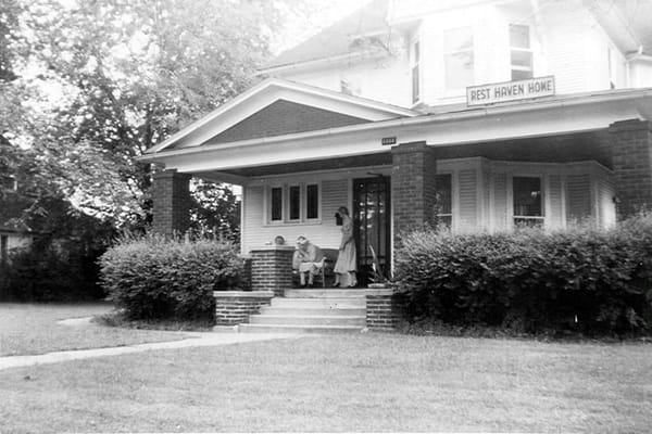 Exterior view of Rest Haven Home with residents on porch