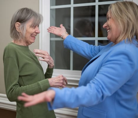 Two women smiling and interacting indoors