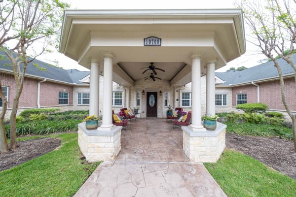Entrance of a senior living facility with porch and landscaping