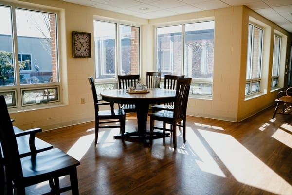 Bright common area with large windows and wooden furniture