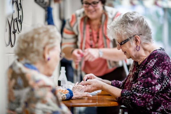 Residents enjoying a manicure session with staff assistance