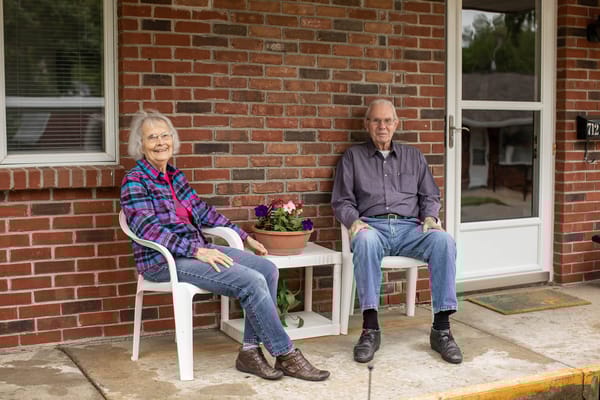 Two residents sitting on a porch with flowers