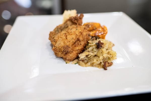 A plate with fried chicken, sides, and sauce