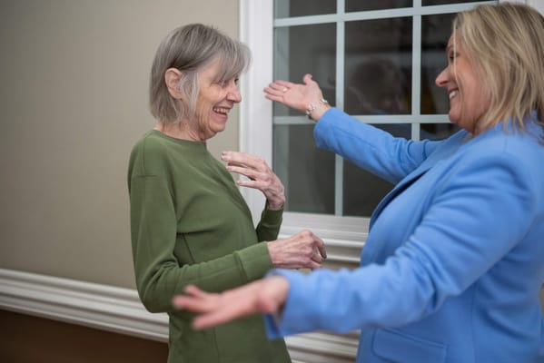 Two women smiling and interacting in a facility interior