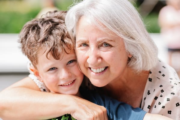 A smiling senior woman with a young boy outdoors
