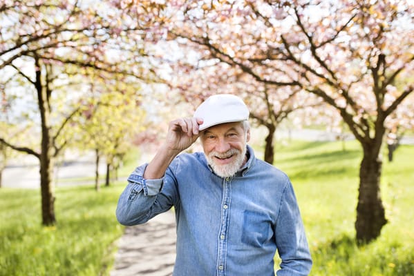 Senior man smiling under blossoming trees