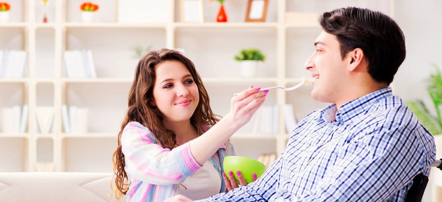 A caregiver feeding a resident in a common area