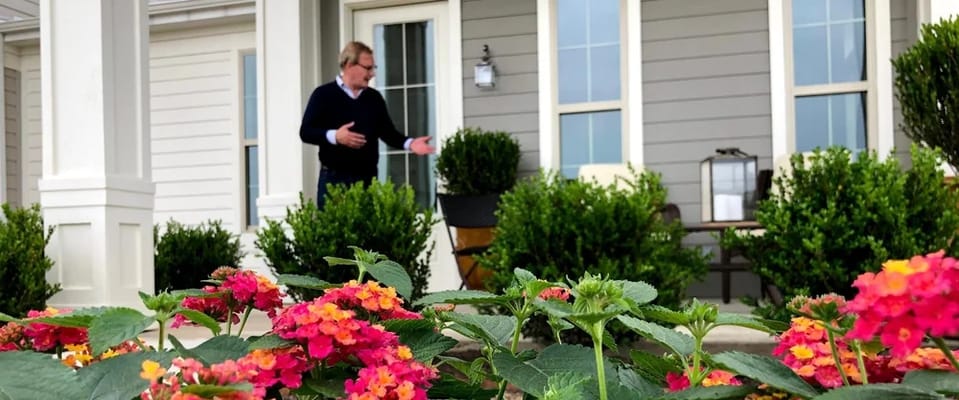A staff member welcoming visitors by blooming flowers