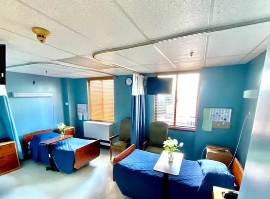 A private room with two beds and chairs