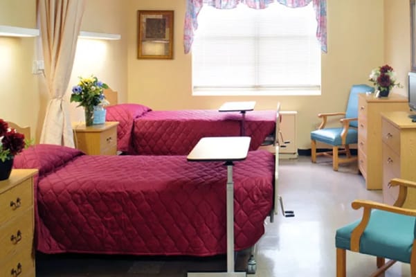 Bedroom with two beds and furnishings in a senior living facility.