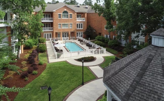 Aerial view of the pool area surrounded by green landscaping at Galleria Woods.