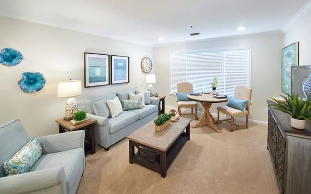 A stylish living room featuring a light blue sofa, wooden coffee table, and dining area with natural light.