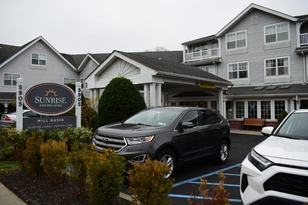 Exterior view of Sunrise at Mill Basin with cars parked in front.