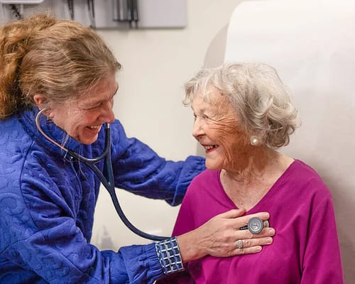 A caregiver smiling at an elderly resident during a check-up