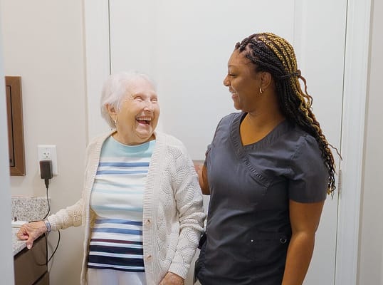 A smiling resident and staff member interacting in a hallway