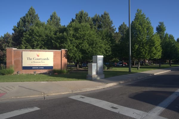 Sign for The Courtyards at Mountain View with greenery in the background