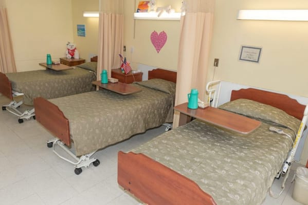 Interior of a resident room with three beds and amenities