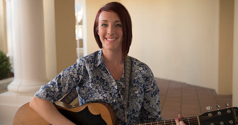 A staff member playing guitar for residents