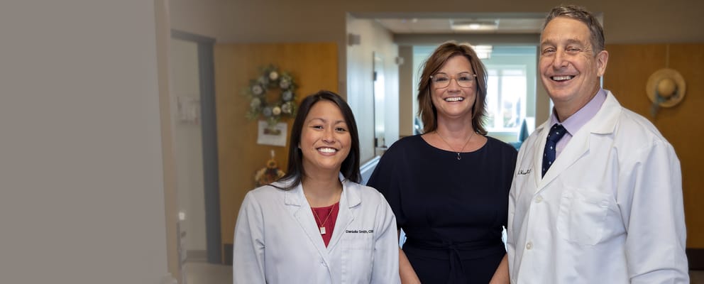 Three staff members posing together in a hallway
