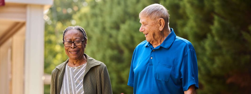 Two residents walking outdoors in a garden area