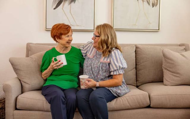 Two women enjoying coffee on a couch