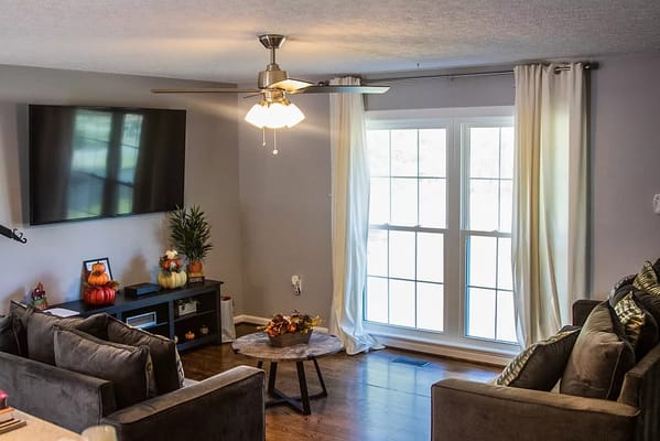 Interior view of a living room with a television, comfortable seating, and decorative pillows.